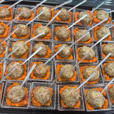 Мини кюфтенца с доматен сос, сервирани в отделни чашки върху плато.